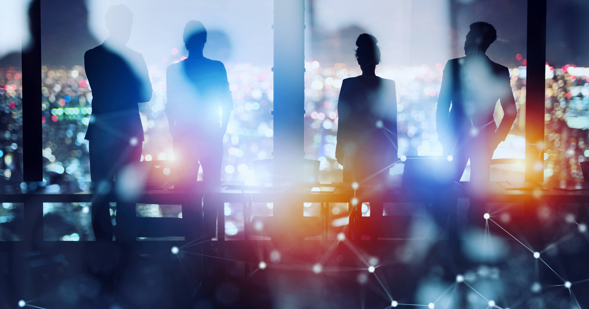 Silhouettes of 4 businesspeople looking out from a tall building in the city. Foreground sparkles.